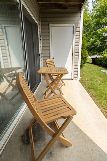 A wooden chair and table are on a patio.